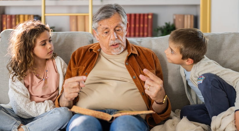 Grandfather reading to a young girl and young boy on the sofa