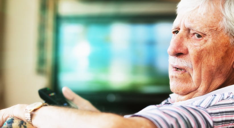 Older man with remote control turning around with an angry look on his face