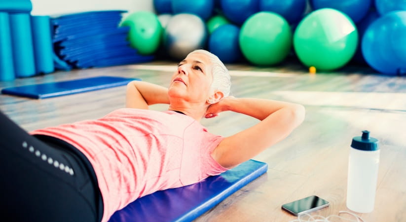 Older woman with short grey hair and pink top doing yoga