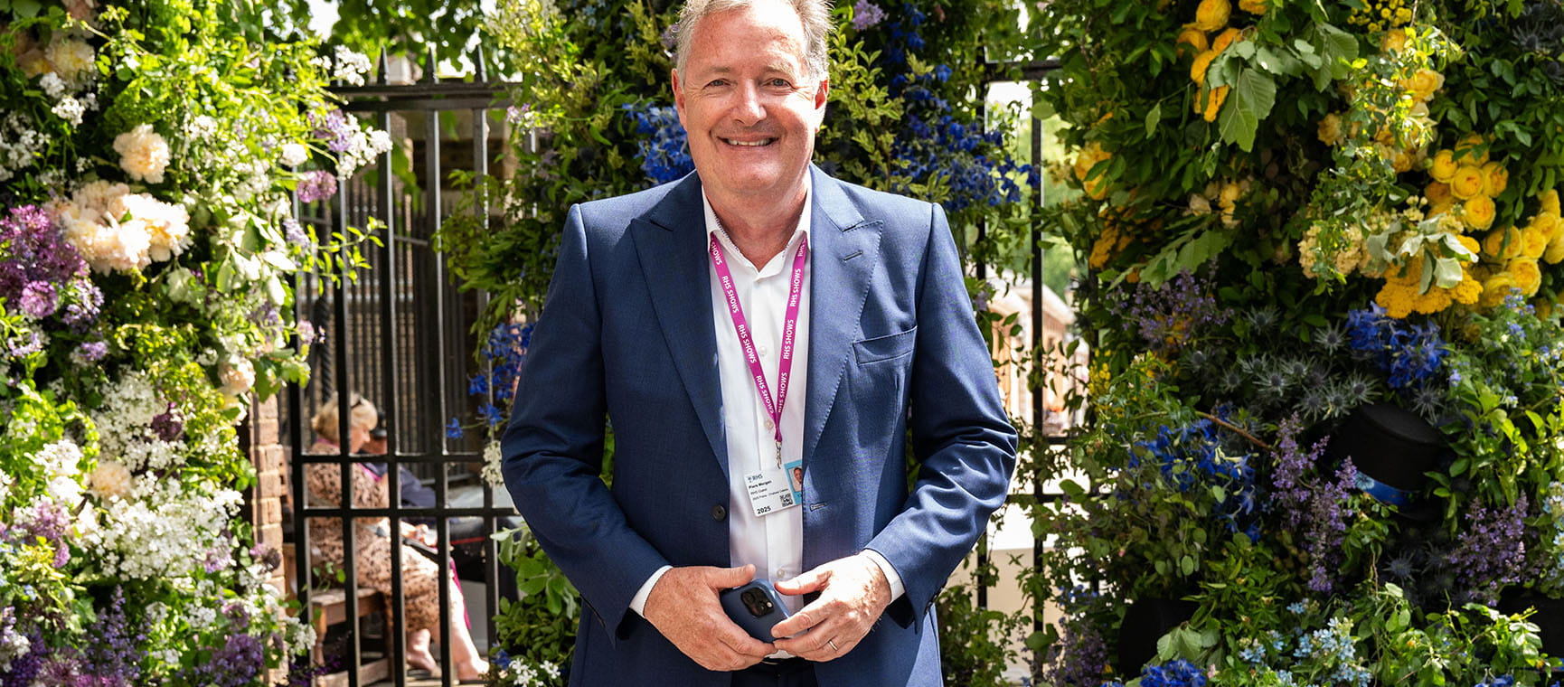 Piers Morgan standing in front of some flowers