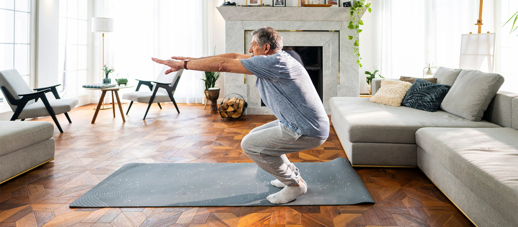 An older man doing squat exercises in his home