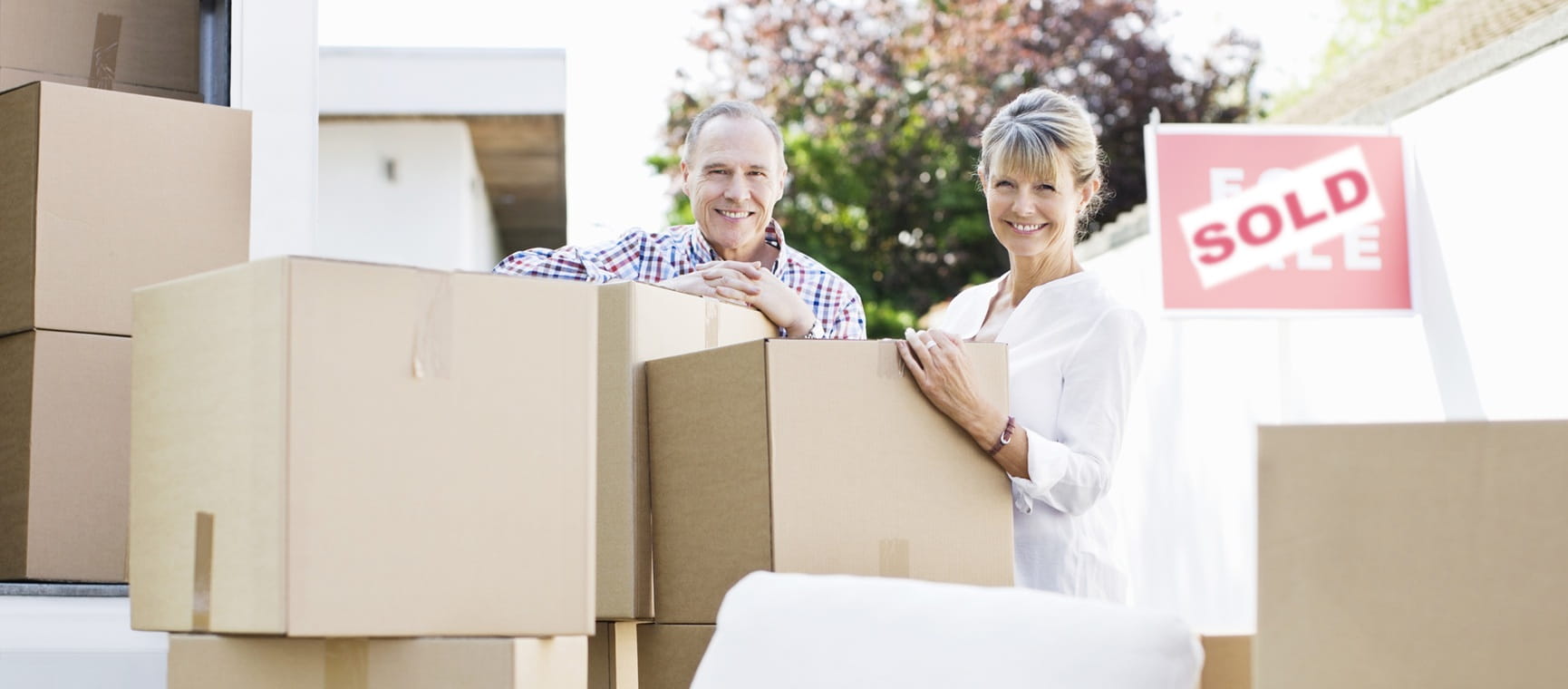Couple standing with boxes and moving van