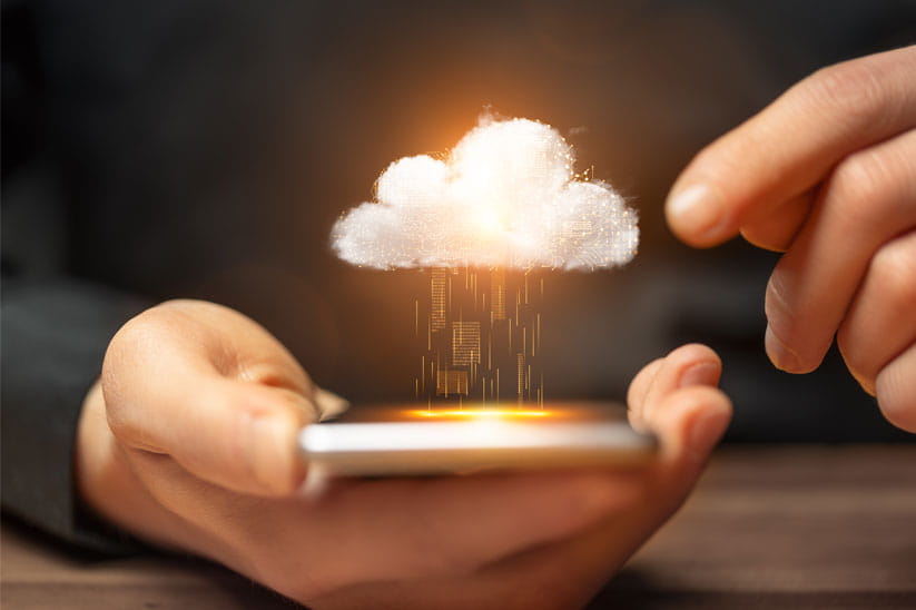 Hand holding a mobile phone with a cloud raining gold data onto it