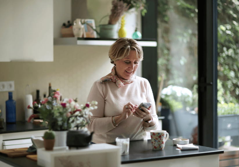 A woman on her phone in her kitchen