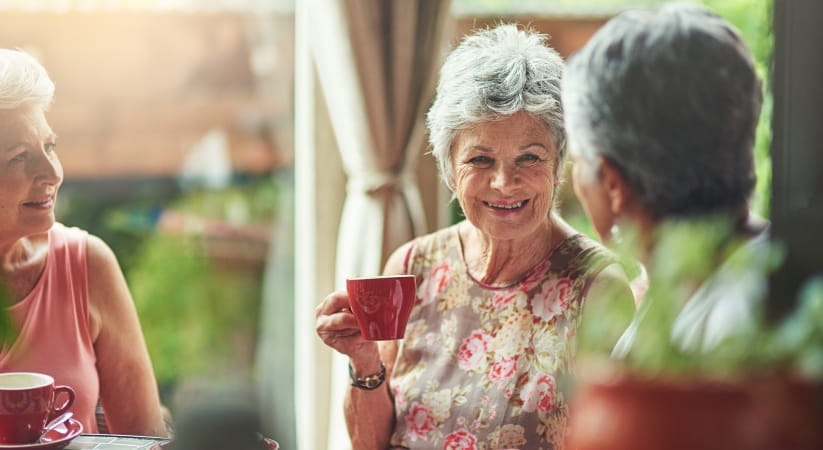 A group of three older ladies enjoying a cup of tea