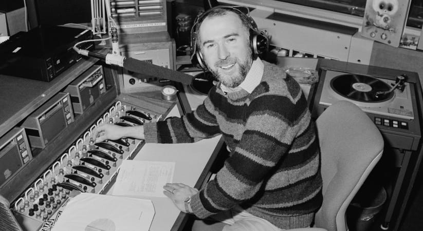 Black and white photo of Ken Bruce sat in his radio studio in 1984