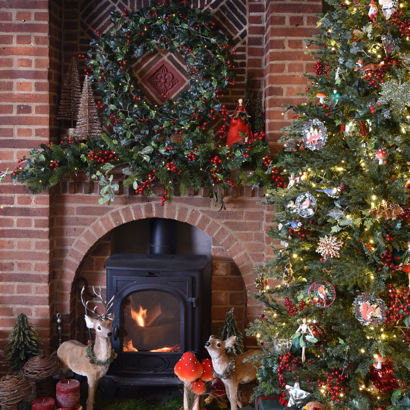 A tree and fireplace decorated with berries, holly and forest animals