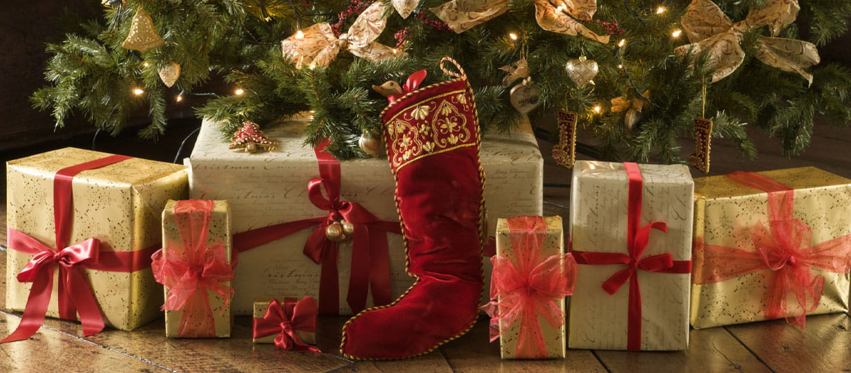 The base of a Christmas tree with a red stocking, and presents wrapped in gold with red bows