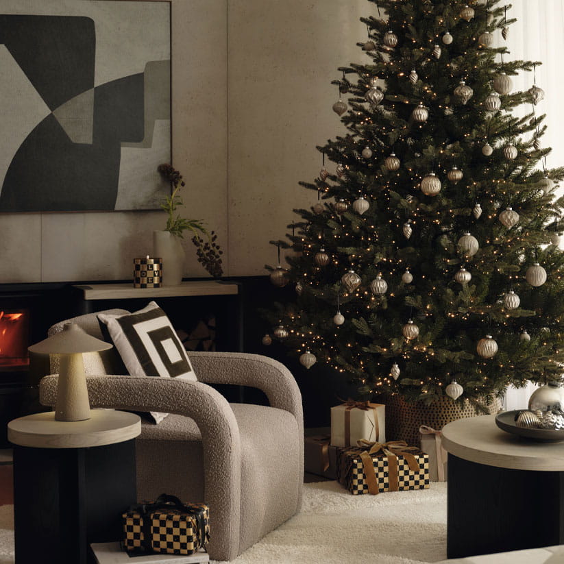 A Christmas tree with white, black and cold wrapped presents underneath it
