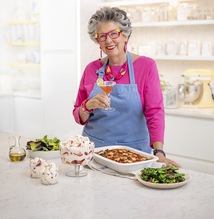 Prue Leith in pink holding a drink