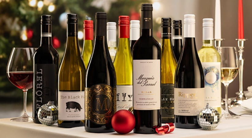 Large group of wine bottles on a table set for Christmas