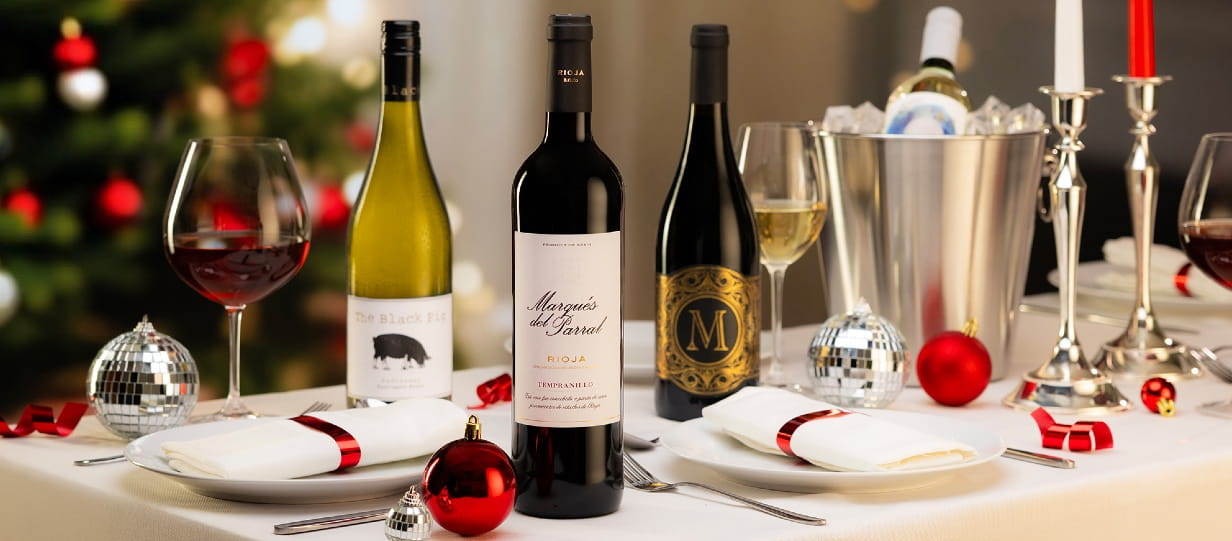 Three mixed bottles of wine stood on a Christmas table