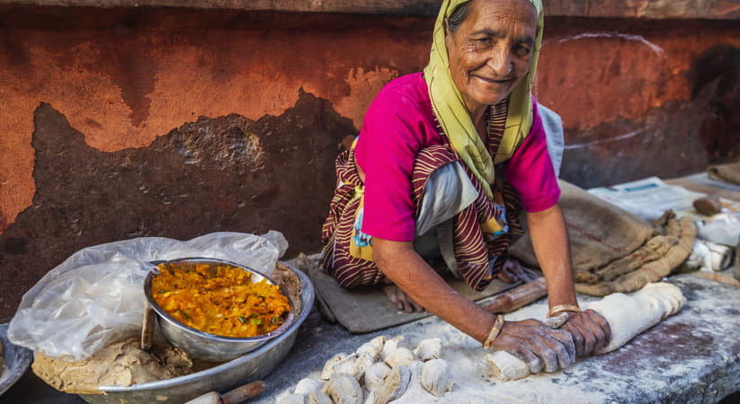 An older Indian woman making bread in the street