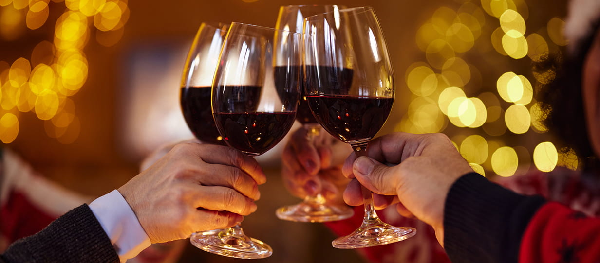 Four glasses of red wine being clinked together