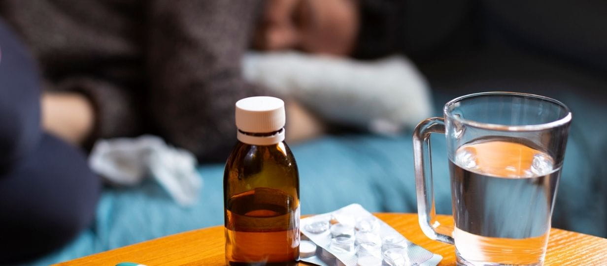 someone in bed with flu with medication on the table