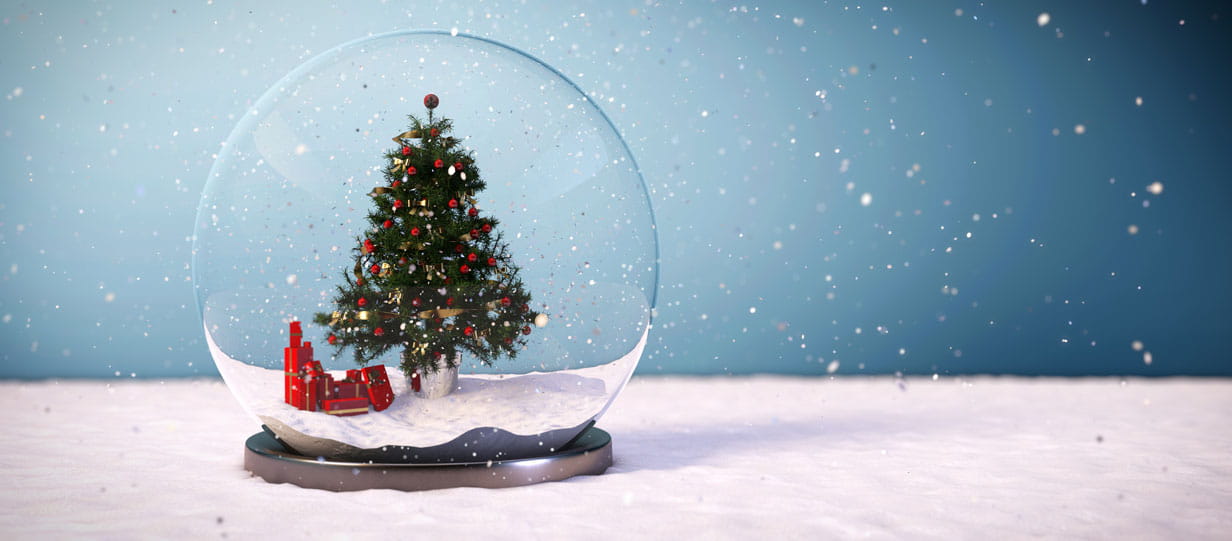 A decorated Christmas tree with presents wrapped in red underneath it in a snowglobe