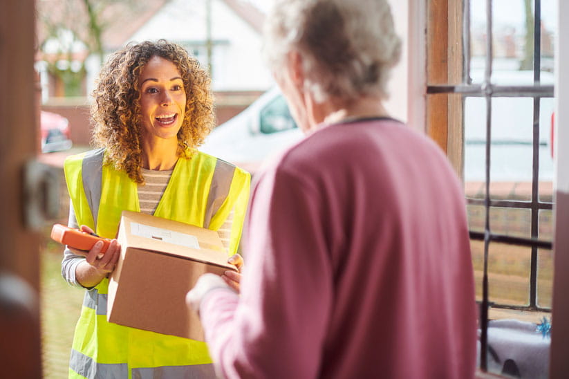 A postie delivering a parcel to an older woman