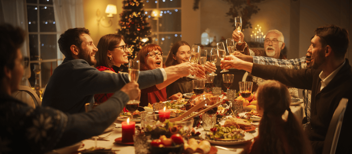 A big family drinking a toast over a Christmas dinner table