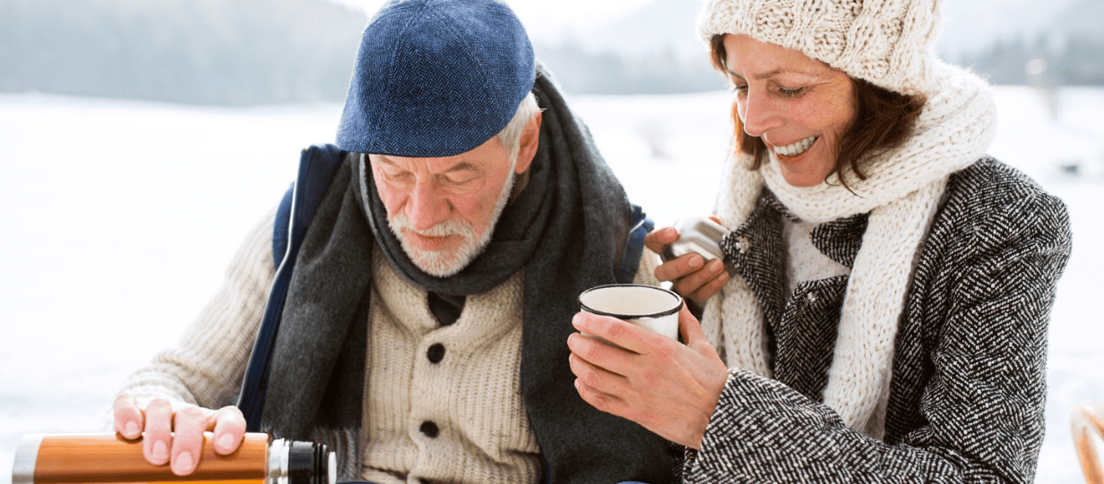 A man and a woman drinking from a thermos on a snowy day