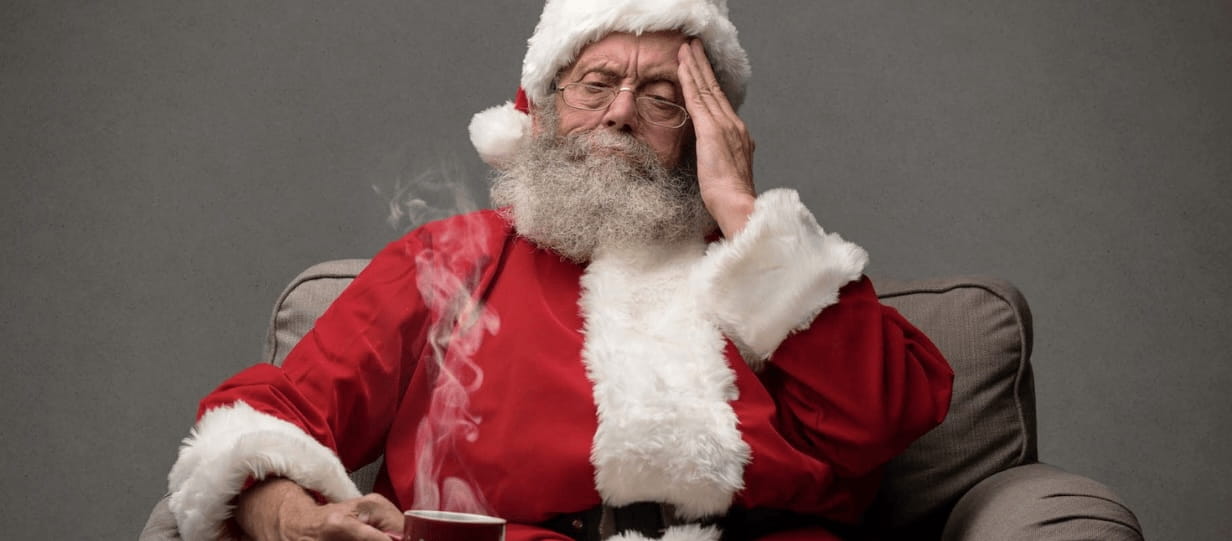 Santa looking tired clutching a mug of drink