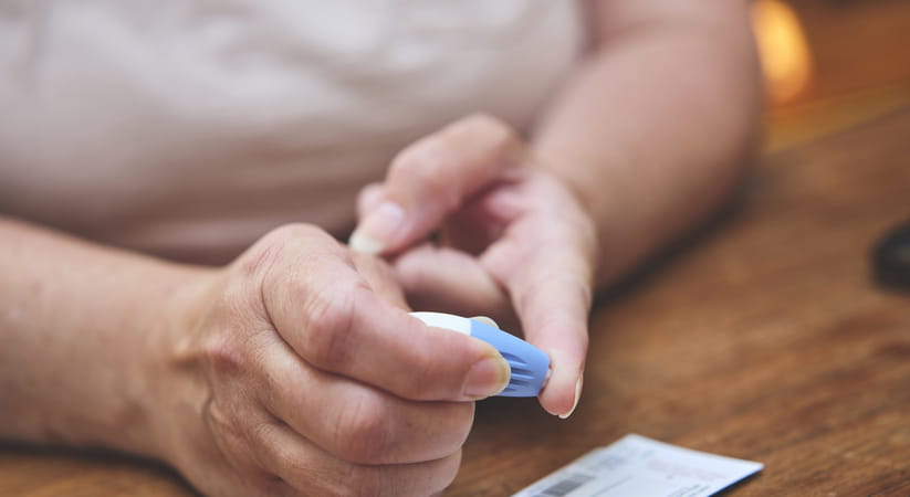 Person in white T shirt taking a finger prick test