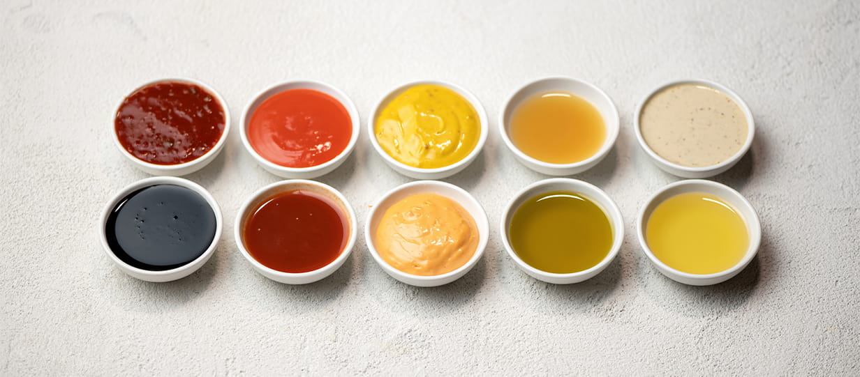 Several bowls of condiments in two rows