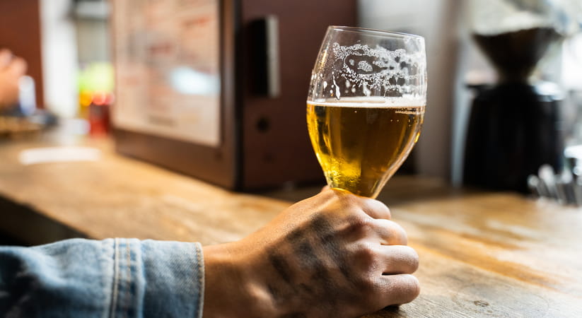 Close up of a male hand holding a half finished glass of beer