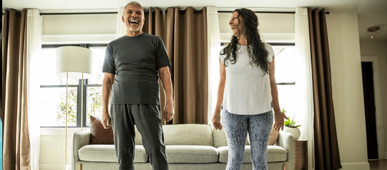 A couple exercising at home and laughing