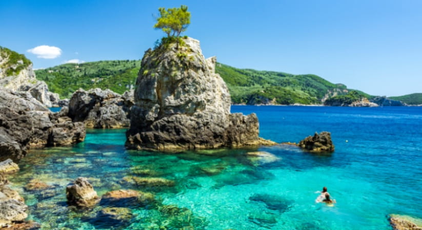 Two people swim in the sea at Grotta Bay on Corfu