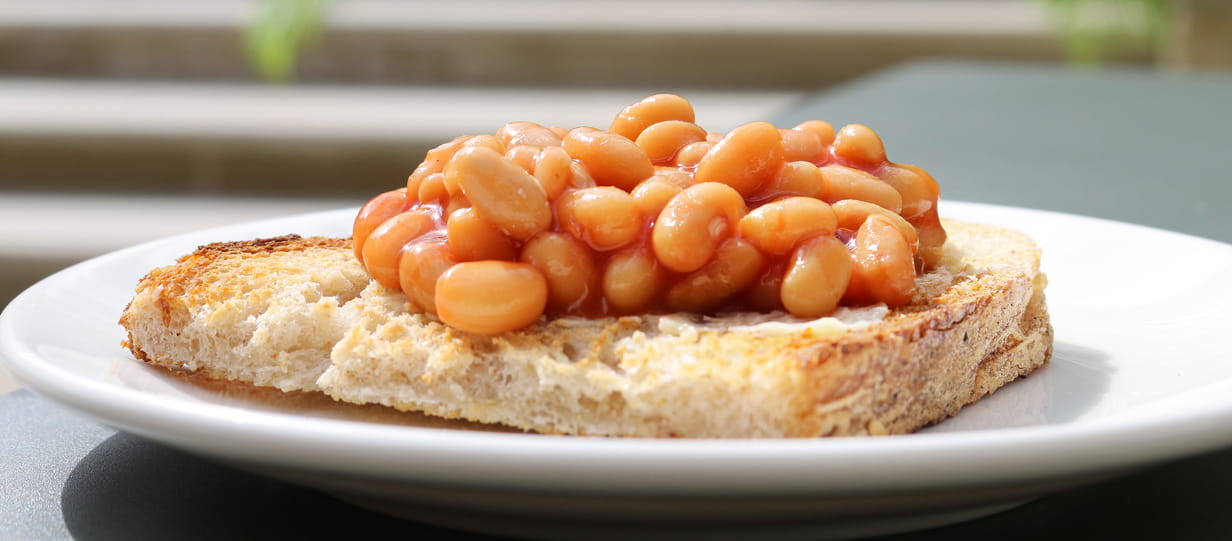 Close up of some baked beans on toast on a white plate