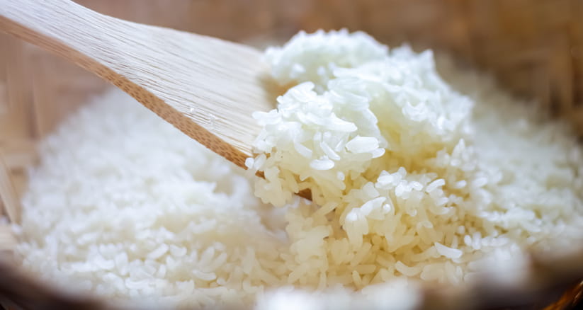 Close up of a wooden spoon in a bowl of white rice