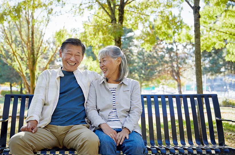 An older couple sitting and laughing on a park bench