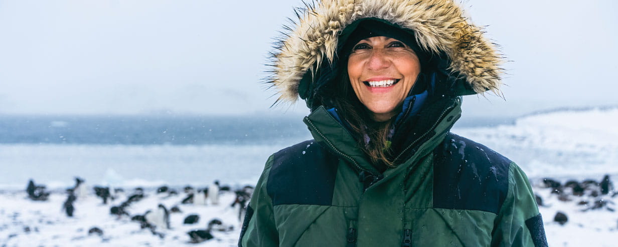 Julia Bradbury in a fur-lined hooded jacket at Yankee Harbour Antarctica with penguins in the background