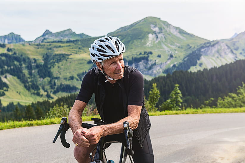An older man in the mountains on his bike and wearing a cycling helmet