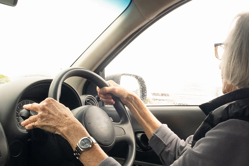 An older woman driving her car with the windows up