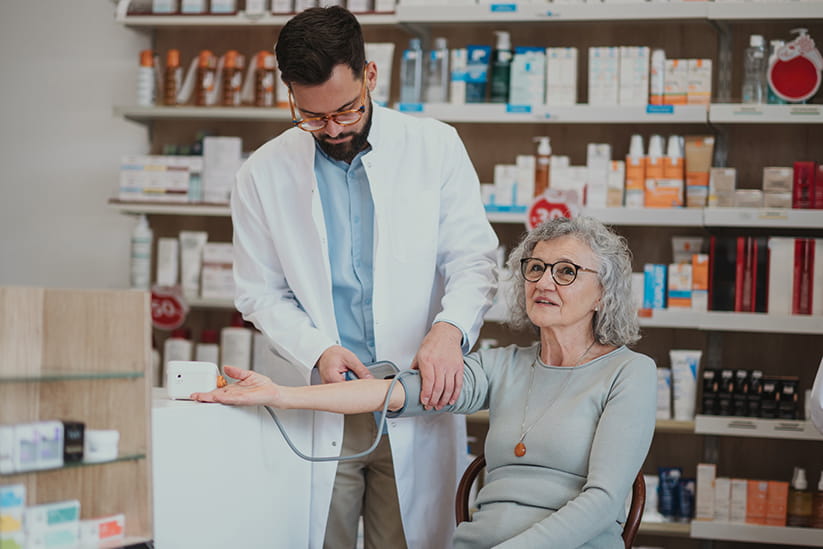 A Pharmacist testing the blood pressure of an older woman
