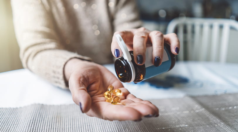 Close up of a person pouring vitamin capsules into their hand