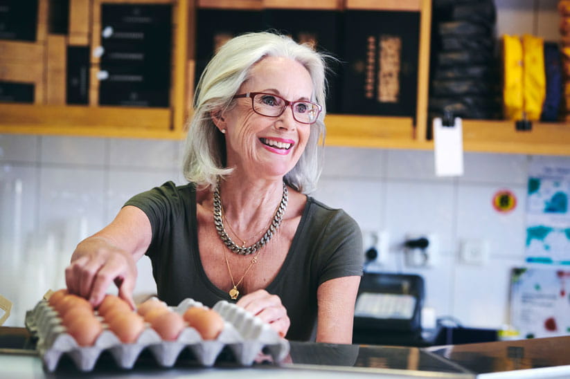 Smiling older woman in a kitchen taking eggs out of a tray