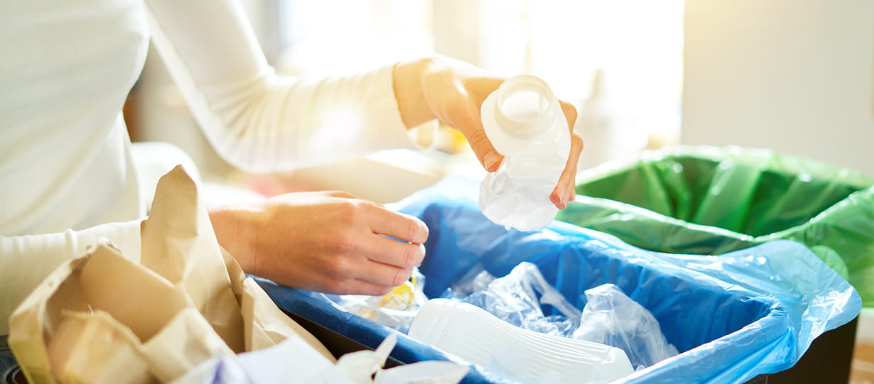 Close up of a woman in a white top doing the recycling