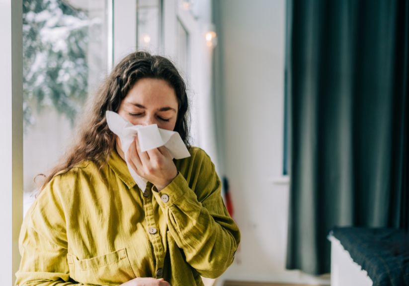 A woman sneezing into a tissue