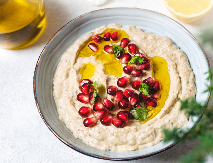 Close up of traditional hummus dip with olive oil and pomegranate seeds