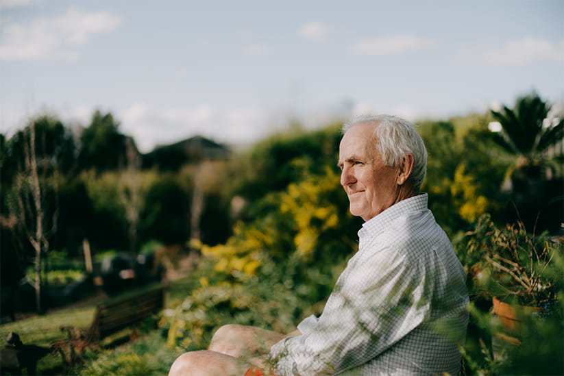 Senior man sitting in a garden and looking at a view