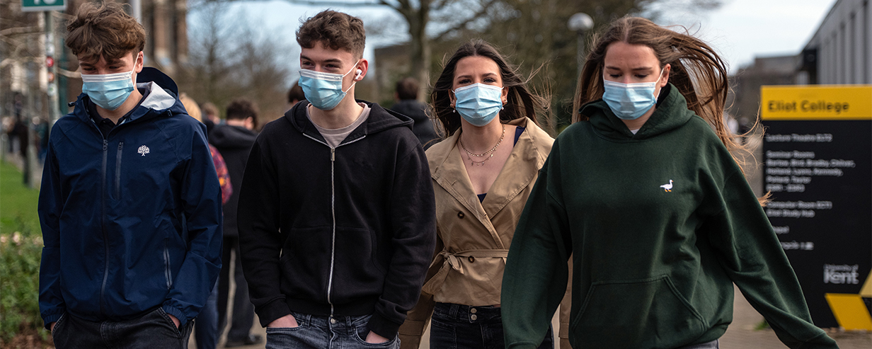 Four students wearing masks whilst walking around the University of Kent following an outbreak of Meningitis