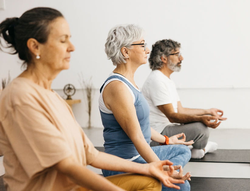 Group of senior people meditating in sukhasana pose in a yoga class