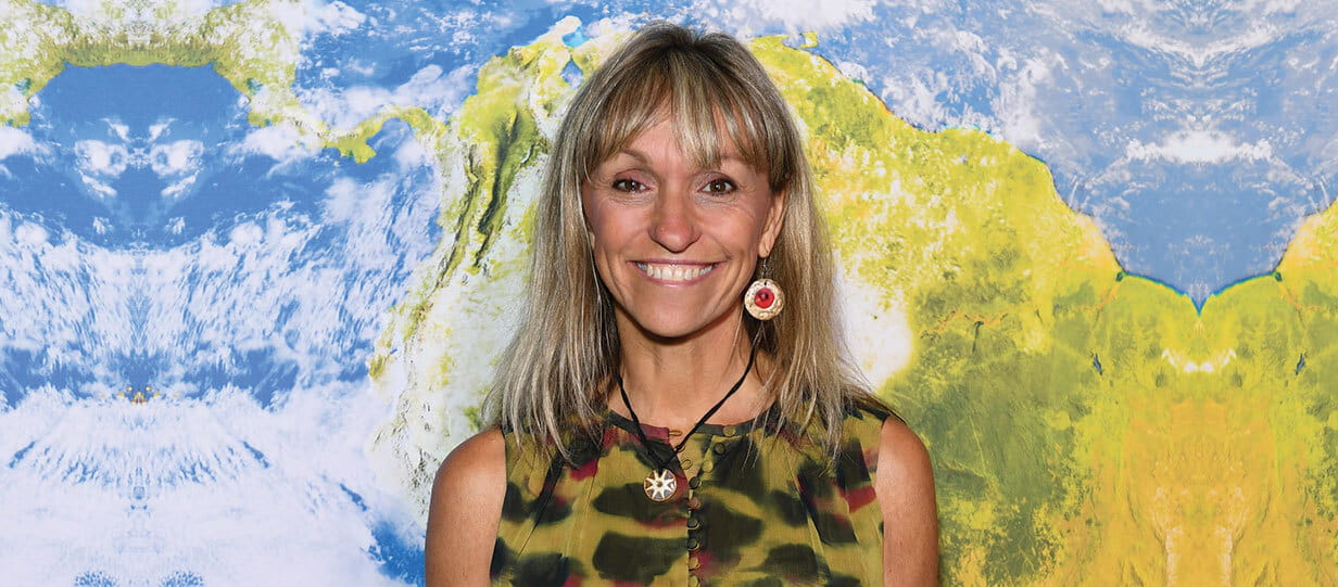 Michaela Strachan smiling in a leopard print sleeveless top against a colourful background