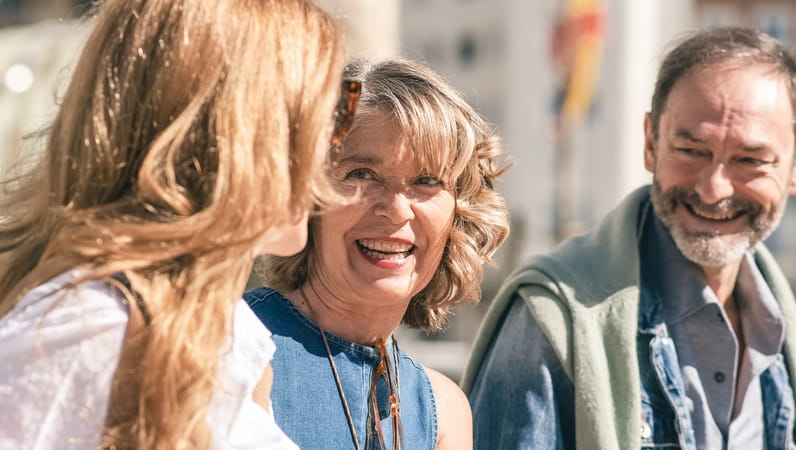 Two older women and an older man chat in the sunshine