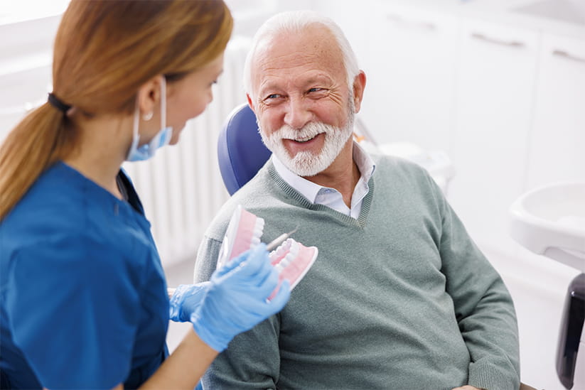 An older man discussing dental health with his dentist