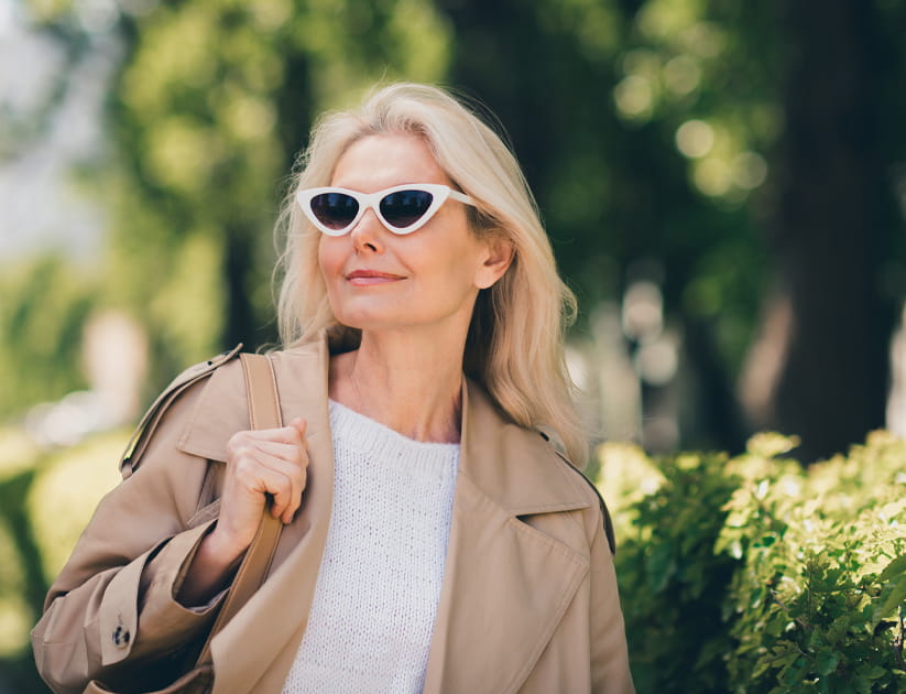 Portrait of cheerful happy retired woman smile spring good mood walk sunglass weekend wear beige coat enjoy outdoors outside park street.