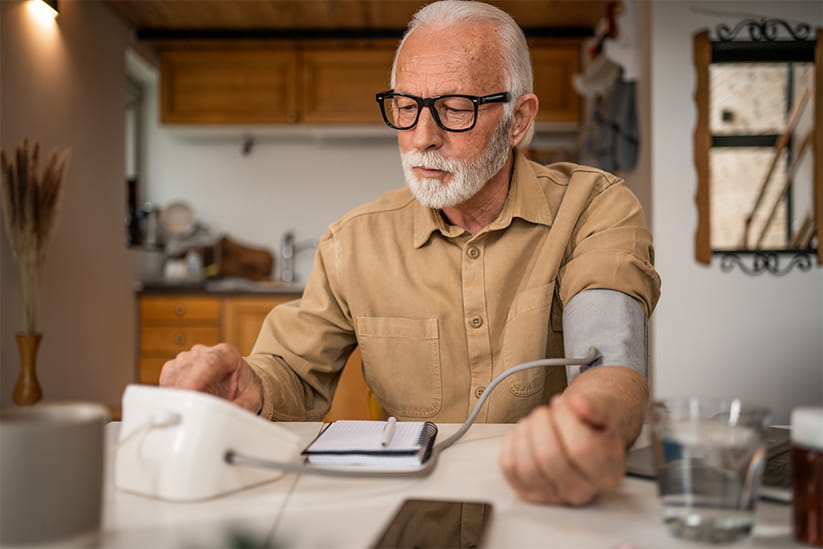 An elderly man measures blood pressure with a digital meter
