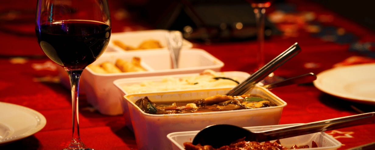 A glass of red wine with a selection of Chinese dishes on a red tablecloth
